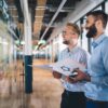 Zwei Männer brainstormen über Optimierungsmöglichkeiten der Prozesse der gesamten Wertschöpfungskette der Versicherung