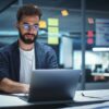 Berater mit Brille sitzt nachts im Office vor Laptop und arbeitet an Operational Excellence